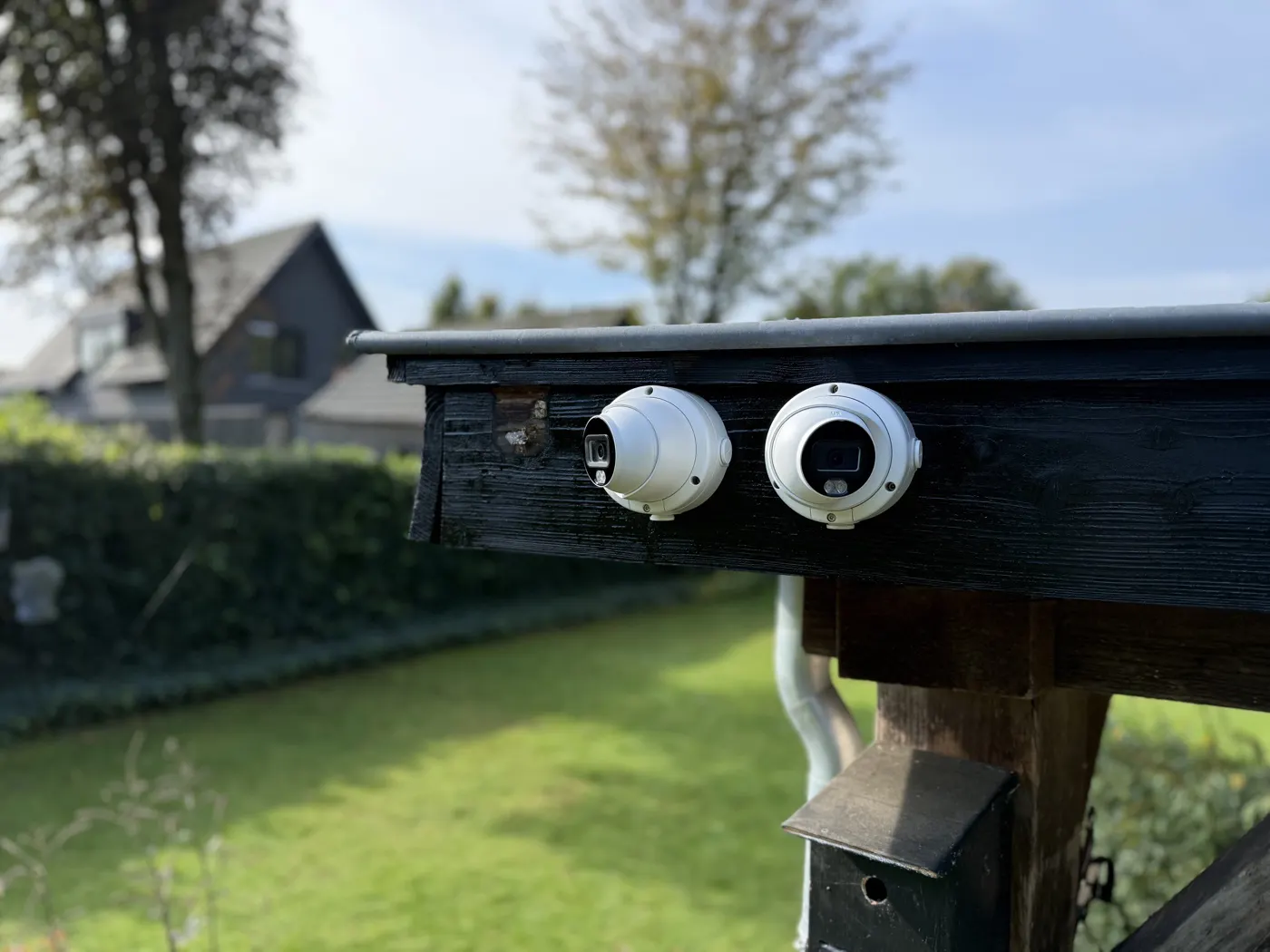 Twee beveiligingscamera's gemonteerd op een houten balk van een overkapping